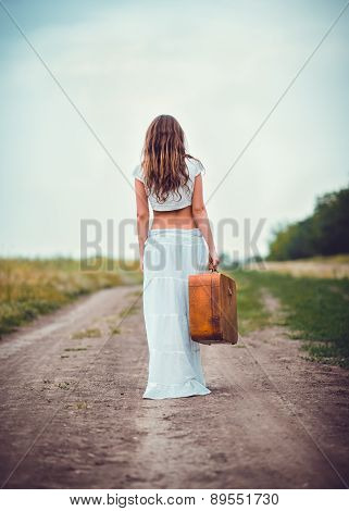 Young Woman With Suitcase In Hand Going Away By Field Road