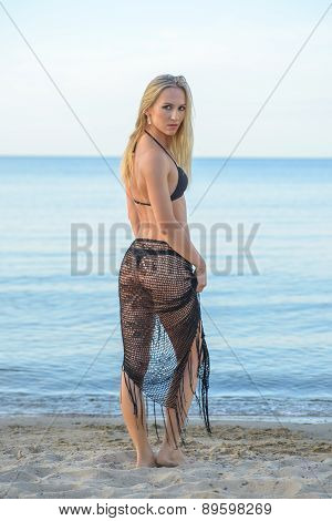 young woman in black bikini posing on a beach