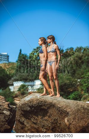two young girls on stones on a beach