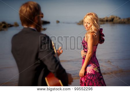 Guitarist Back-view And Blonde Girl Against Sea