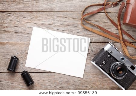 Vintage film camera and blank photo frame on wooden table. Top view