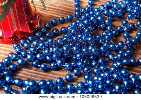 Blue Beads With Red Christmas Bell On Old Wood Background