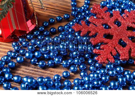 Large Red Snowflake, Red Bell And Blue Beads On Wood Background