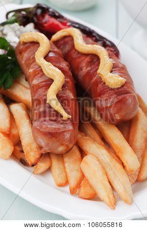 Grilled sausages with mustard and french fries, popular fast food meal