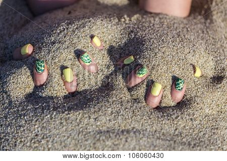 Female Hand With Beautiful Nail Polish Playing With Sand