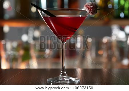 Red alcohol cocktail with sugared cherry on the bar counter, close up