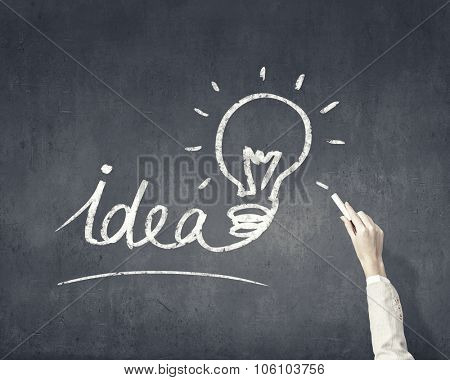 Human hand darwing light bulb as idea concept with chalk