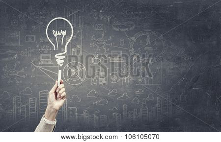 Human hand darwing light bulb as idea concept with chalk