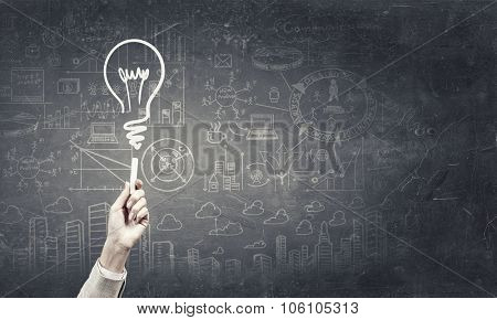 Human hand darwing light bulb as idea concept with chalk