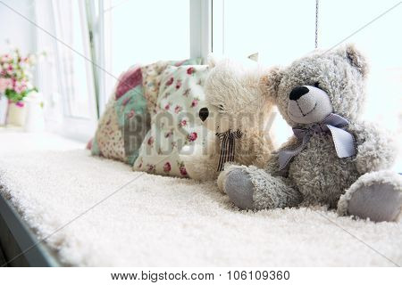 Two Teddy Bears And Two Pillows On A Light Windowsill