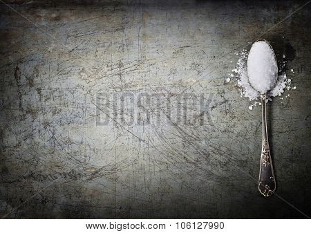 silver spoon filled with salt on rustick background
