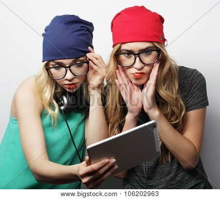 two hipster girls friends use digital tablet, studio shot over gray vackground