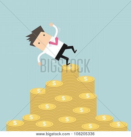Businessman falling of money mountain