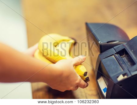 sale, shopping, payment, consumerism and people concept - close up of hands buying or scanning bananas at checkout in food market or mall