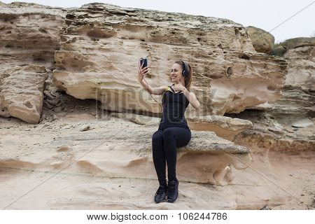 Portrait of young fit woman making self portrait showing super sign for smart phone camera