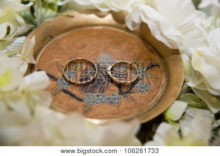 Two  wedding rings lie in treelake near flowers