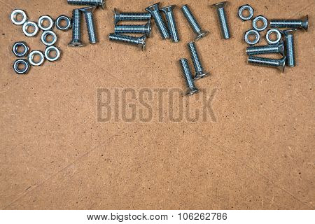 Steel bolts and nuts on fibreboard