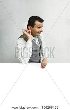 Brazilian man holding earlobe behing a advertising with a copyspace.