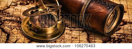 Travel geography navigation concept background - letterbox panorama of old vintage retro compass with sundial and spyglass on ancient world map