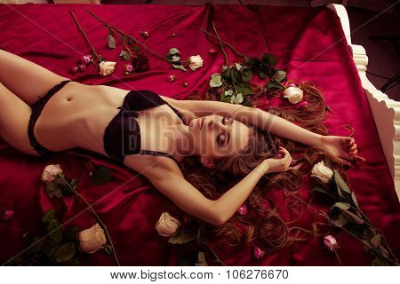 Sexy Slim Girl In Lingerie Lying On The Red Bed With Flowers