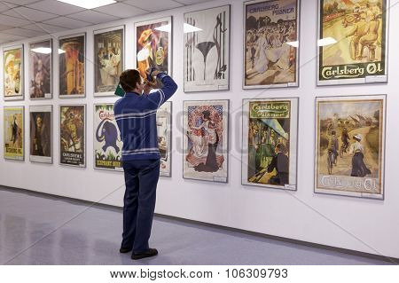 ST. PETERSBURG, RUSSIA - OCTOBER 24, 2015: Tourist making photo of beer posters at the Baltika - St Petersburg brewery during the October Beer Festival. The brewery provides guided tours to the plant