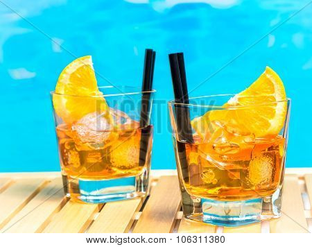 Two Glasses Of Spritz Aperitif Aperol Cocktail With Orange Slices And Ice Cubes On Swimming Pool Bac