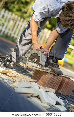 Young Man Working In His Back Yard Using Circular Saw