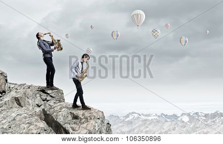 Duet of young man and woman musicians playing saxophones