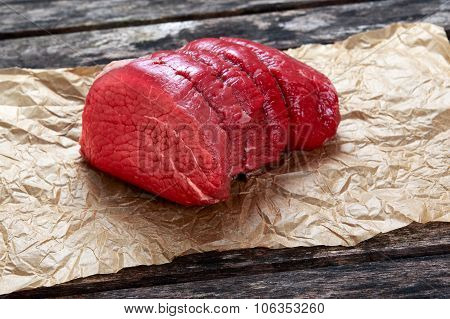 A Pieces Of Fresh Meat, Beef Slab On Crumpled Paper On Old Wooden Table. Ready To Cook.