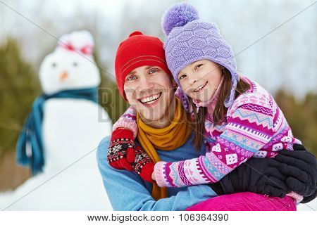 Father and daughter with snowman