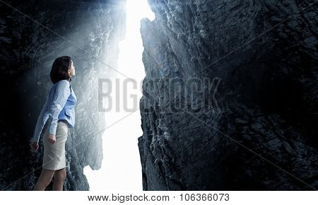 Young businesswoman making fists and reaching light in wall crack