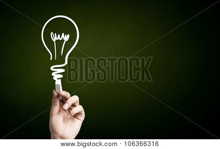 Human hand darwing light bulb as idea concept with chalk