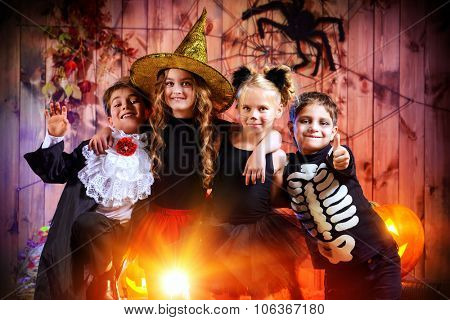 Cheerful children in halloween costumes celebrating halloween in a wooden barn with pumpkins. Halloween concept.