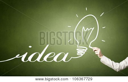 Human hand darwing light bulb as idea concept with chalk