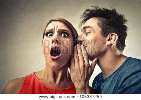 Man whispering into a woman's ear