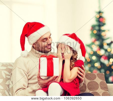 family, christmas, x-mas, winter, happiness and people concept - smiling daughter with closed eyes waiting for a present from fathe