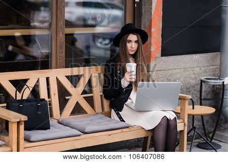 Young beautiful female enjoying coffee during work on portable laptop computer
