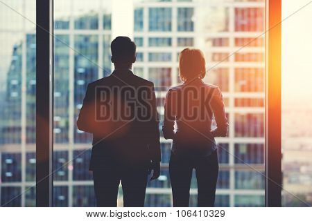 Team of businesspeople in fear or risk watching cityscape from skyscraper interior
