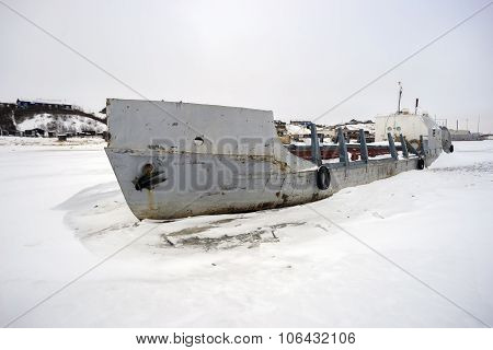 Abandoned fishing boat in a frozen river.
