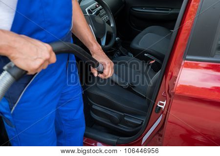 Worker Vacuuming Car With Vacuum Cleaner
