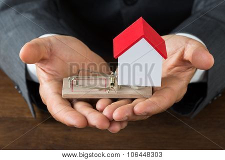 Businessman Holding Model House On Rattrap