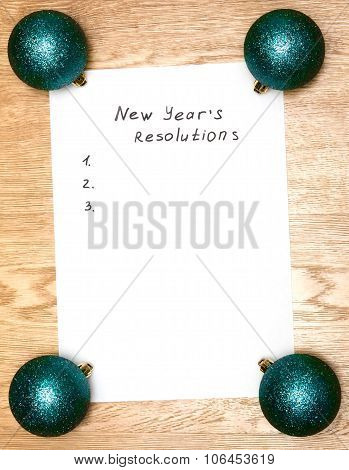 New Year's Resolutions On A Blank List On Wooden Background / With New Year Bright Pink Balls