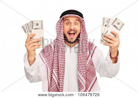Excited young Arab holding few stacks of money and looking at the camera isolated on white background