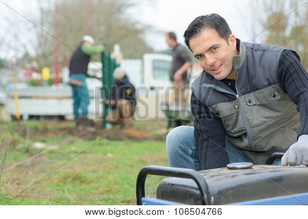 Builder kneeling by a generator
