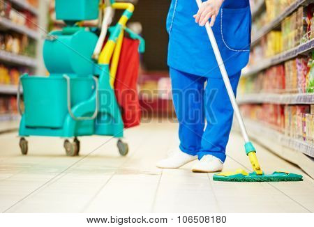 Female cleaner worker in uniform  with mop cleaning the floor of supermarket shop store