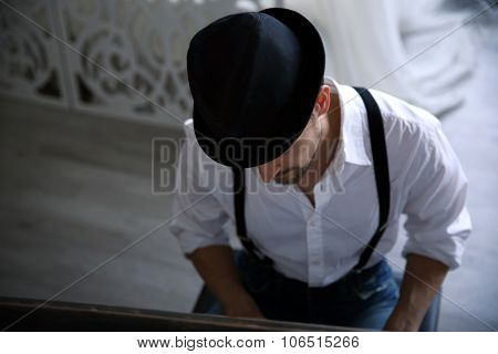 Handsome young man in hat making piano music, topside view