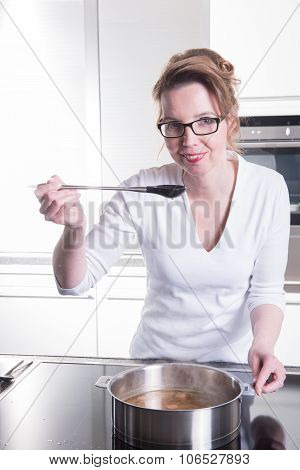 Attractive Woman In Modern Ktchen Cooking And Tasting