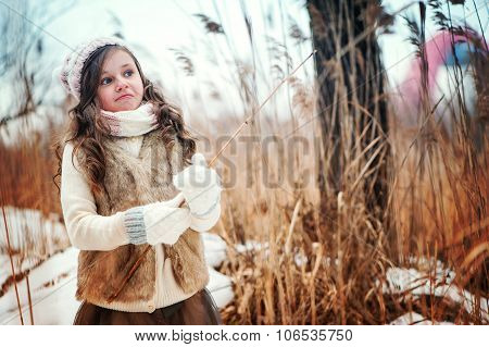 adorable dreamy kid girl on the walk in winter forest
