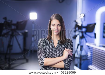 Young beautiful brunette television announcer at studio standing next to the camera.TV director