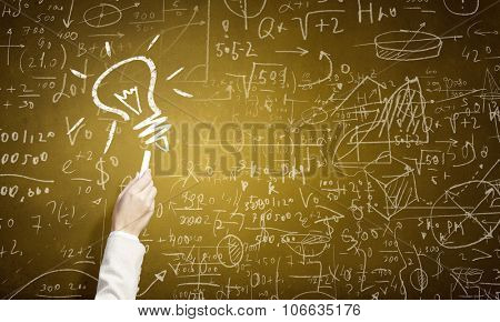Human hand darwing light bulb as idea concept with chalk